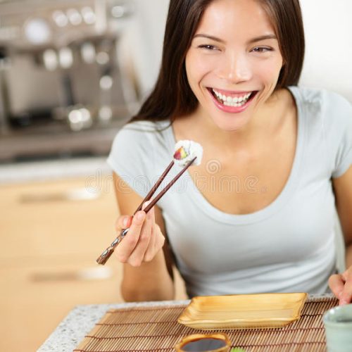 donna-che-mangia-i-bastoncini-della-tenuta-di-maki-dei-sushi-40737179